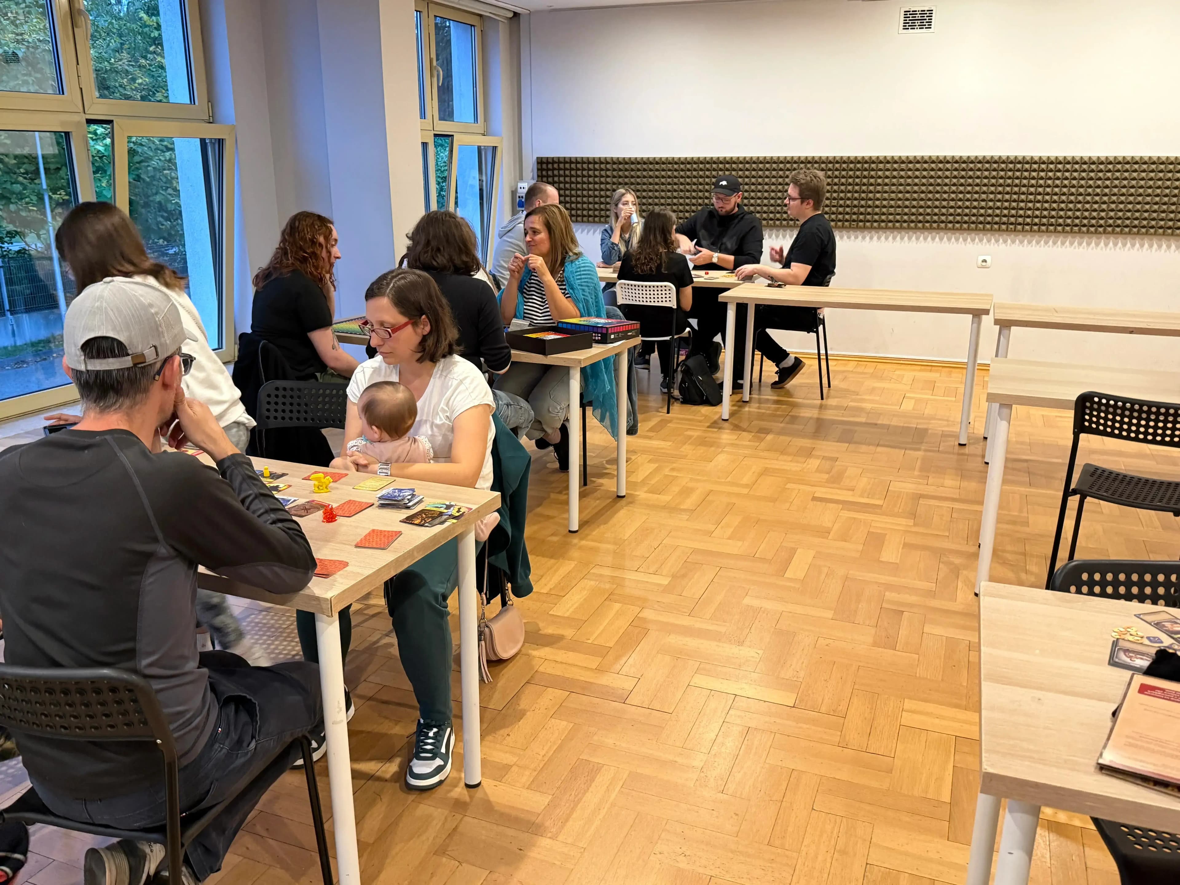 Gracze przy kilku stolikach grają w gry planszowe
